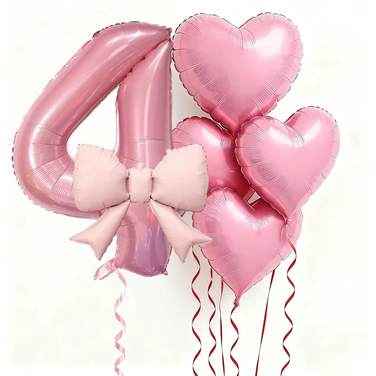 Pink foil balloons shaped like the number 4 and hearts with pink bows for party decoration