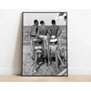 A black and white photograph of four people posing on a beach with a ladder.