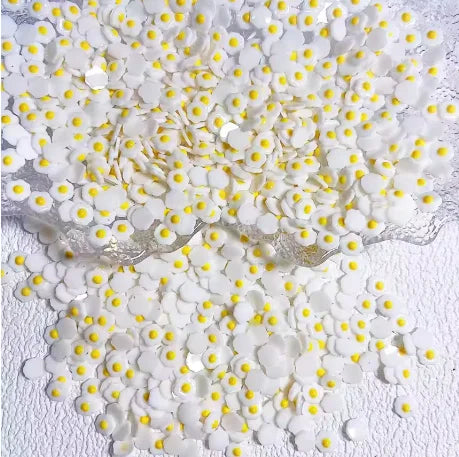 Pila de 50 aderezos de uñas de tortuga mini coloridos esparcidos sobre una superficie blanca.