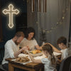 A family is gathered around a wooden table, interacting with a glowing white neon cross wall sign.