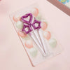 A set of gradient blue metallic birthday candles with purple star-shaped toppers and pink and green wax candles.