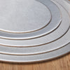 Stack of silver coated round cake boards with concentric rings on a wooden surface