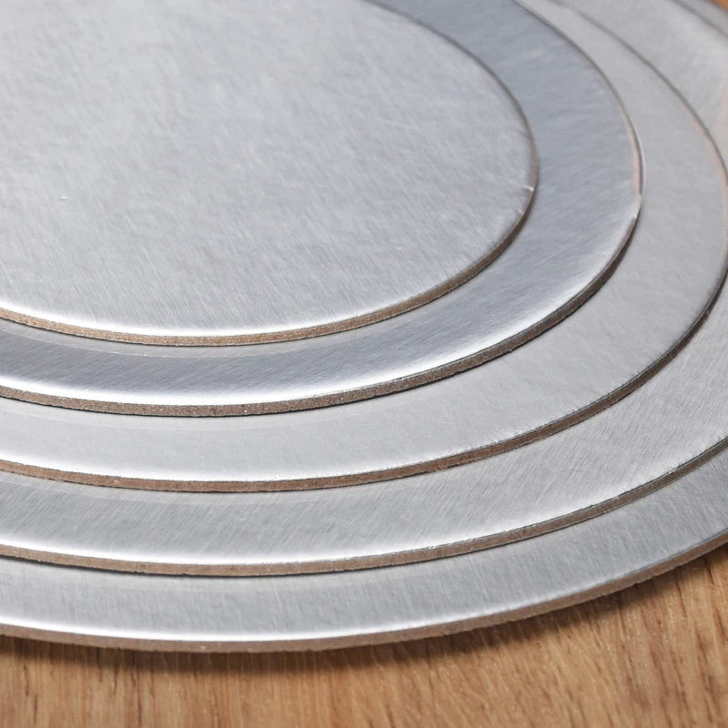 Stack of silver coated round cake boards with concentric rings on a wooden surface