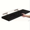 A hand is holding a dark wood floating wall shelf with hidden metal brackets.