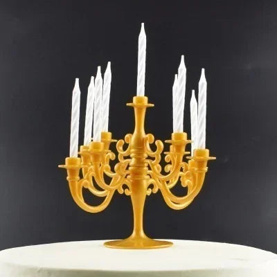 A golden candelabra holds nine white candles for an elegant birthday cake decoration.
