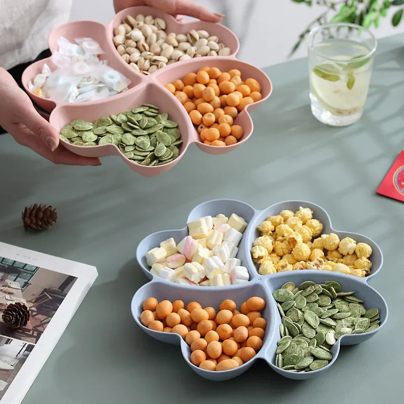 A heart-shaped four-compartment snack tray filled with various nuts, seeds, and dried fruits.