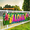 A vibrant tropical floral banner with the word ALOHA printed on it, displayed outdoors against a white fence.