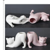A pair of ceramic cartoon cat planters, one white and one pink, featuring a tail design.