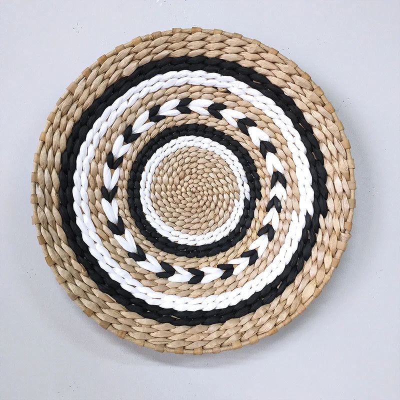 Round woven straw wall decor hanging with concentric black and white patterns.