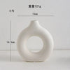 A white, smooth, organic-shaped vase with a wide opening, shown against a white background.