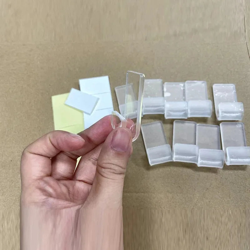 A hand holds a set of ten clear acrylic vinyl record display racks on brown cardboard.