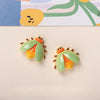 Two small resin insect magnets featuring orange and green butterfly or bee designs against a light background.