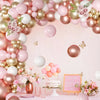 A pink and gold latex balloon garland featuring various sized balloons and floral accents for a celebration.