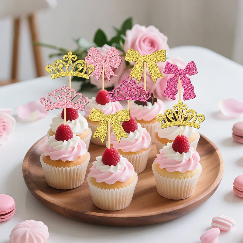 A display of pink and gold elegant crown and bow cupcake toppers on a wooden platter.