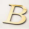 A gold acrylic mirror letter B wall sticker with a black outline.