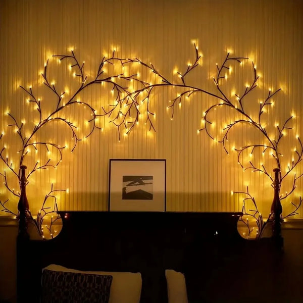 A decorative arrangement of glowing willow branches illuminated by string lights above a dark mantelpiece.