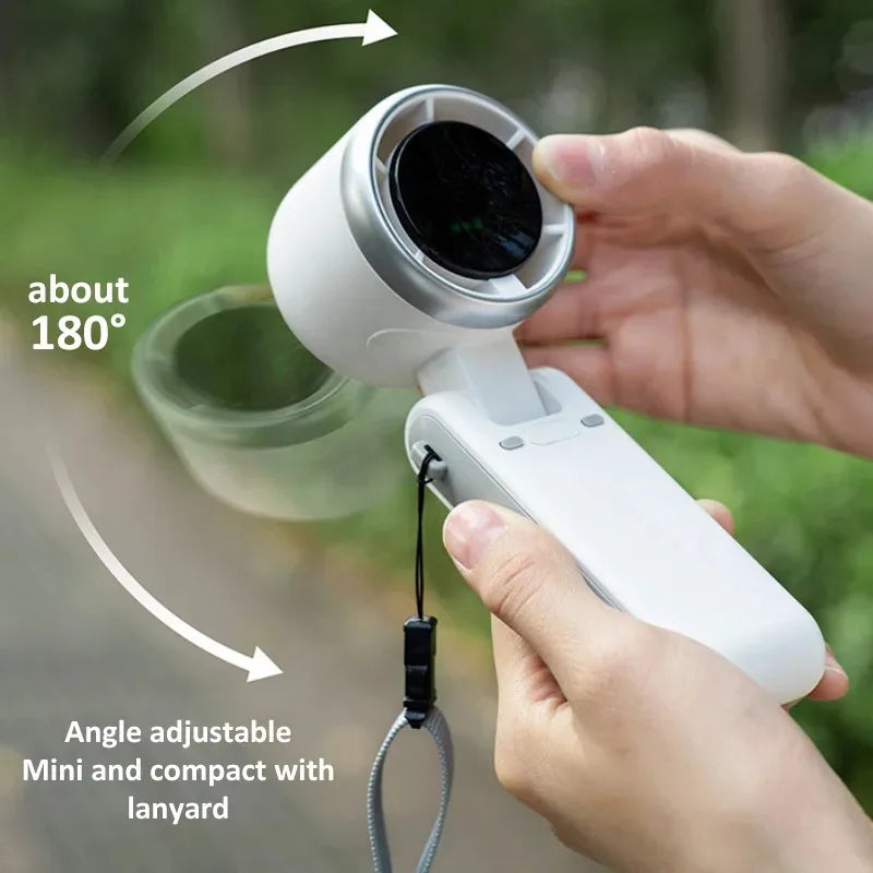A hand holds a white, angle-adjustable mini fan with an 180-degree rotation feature and a lanyard.