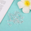 A collection of mini clear plastic spring clips for photos, papers, and crafts resting on a light blue background next to a w