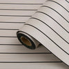 Roll of self-adhesive 3D wood grain wall panels with black stripes laid on a light wooden surface.