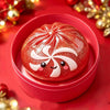 A red squishy stress reliever shaped like a smiling snowman with white details, resting in a pink container on a red backgrou