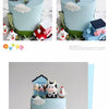 A tiered cake display featuring farm animal toppers including a black and white bear, a pink pig, and a white bird on light b