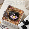 A massage candle in an anti-scalding tin rests in a wooden box surrounded by dried lavender and peach petals.