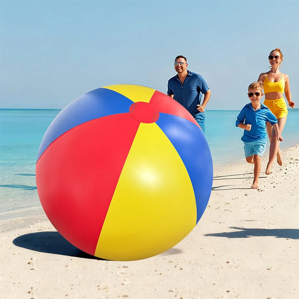 A large red and yellow inflatable pool party ball is lying on a sandy beach with two adults and a child nearby.