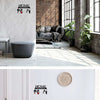 A metal key holder with wall mounted hooks is displayed on a white wall and a wooden floor.