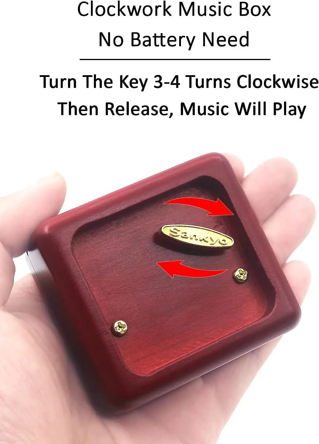 A hand holds a red wooden clockwork music box with a key and a small golden piece.
