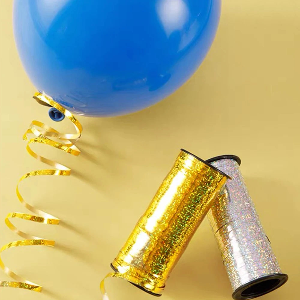 Two rolls of glitter curling ribbon for gift wrapping and party decor are shown against a light yellow background.
