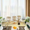 A three-arm gold crystal candelabra displayed on a table with white linens and floral arrangements.