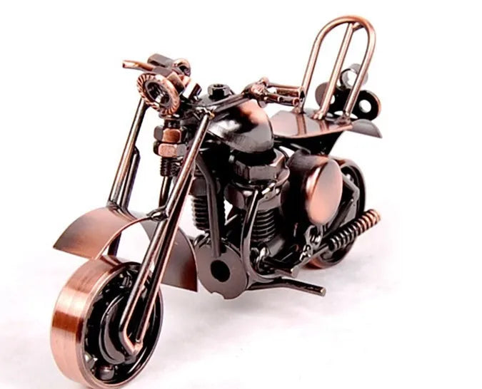 A handcrafted metal motorcycle model with brass and black components displayed against a white background.