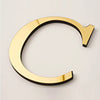 Gold acrylic mirror letter wall sticker shaped like a cursive C with an arrow tip