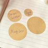 Several round kraft paper labels are placed on lined paper, including labels for peanut butter, thank you, and mung bean.
