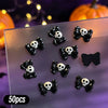 A variety pack of 50 black and white skull resin nail charms displayed on a clear surface.