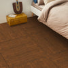 A close-up view of brown wood grain flooring with a yellow trunk and pillows in the background.