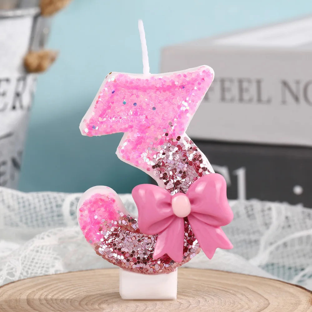 Pink glitter number 3 candle with a pink bow on a white stand for birthday celebrations