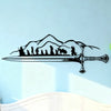 Black silhouette wall art featuring a mountain range and a sword with figures beneath it.