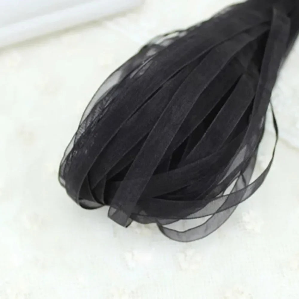 A bundle of black decorative fishtail yarn ribbon laid on a white surface.