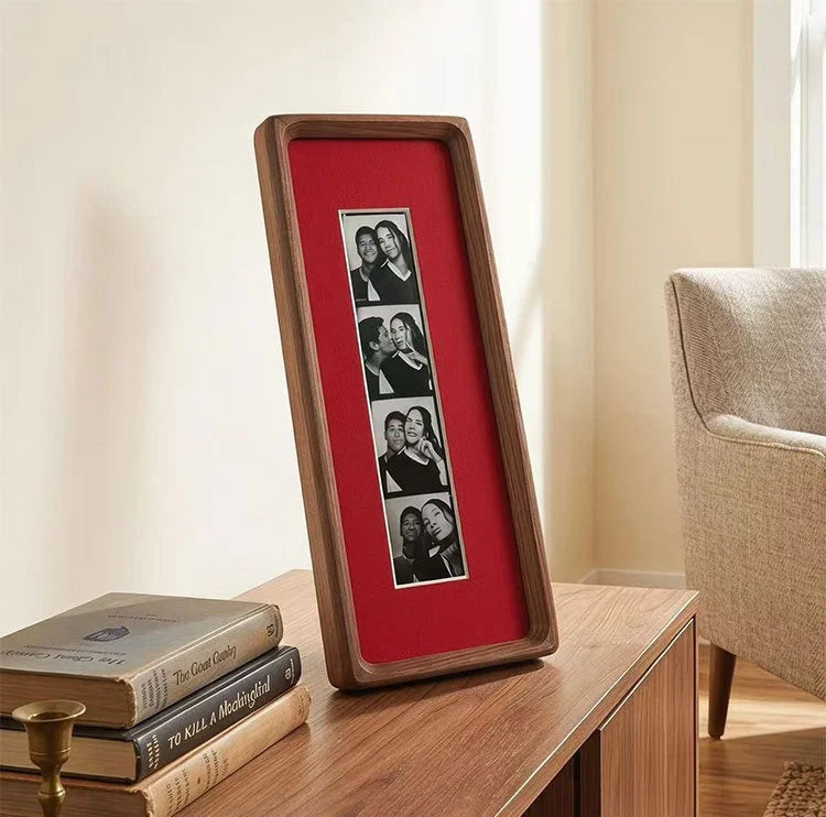 A wooden photo strip frame with a red background displaying several small photographs.