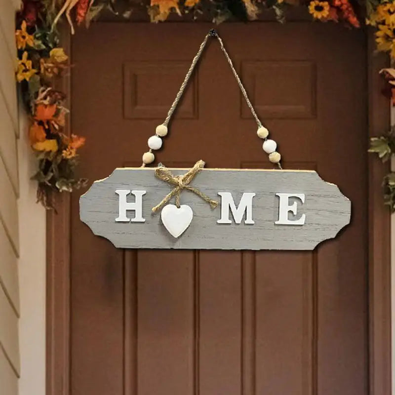 A wooden welcome sign with the word HOME carved into it, hanging on a door with dried floral garlands.
