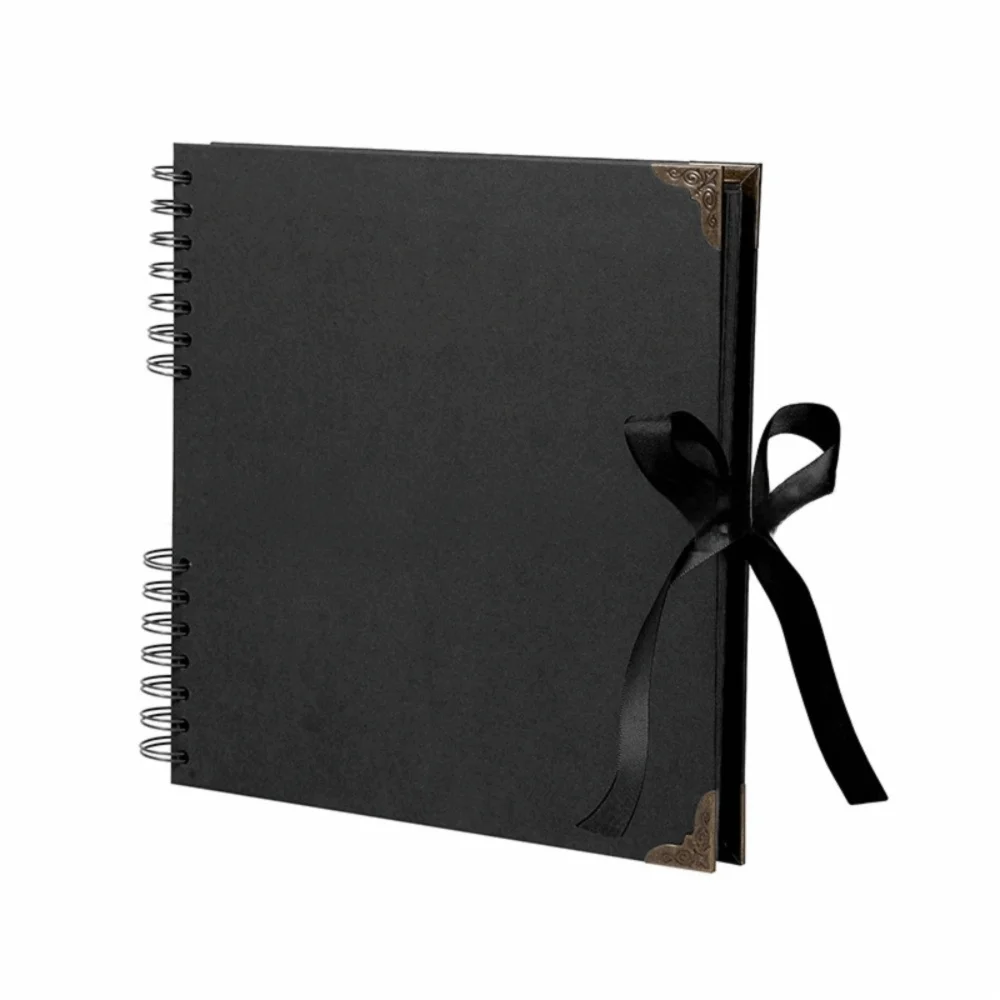 Bloc-notes album photo noir à plat avec couverture bordée d'or et attaché avec un ruban noir.