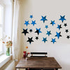 A wall display of blue and black star-shaped acrylic mirror decor on a white wall next to a window.