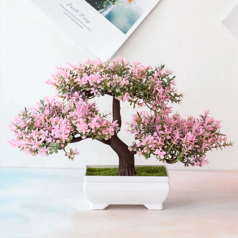 Un faux arbre bonsai réaliste avec des fleurs roses, présenté dans un pot blanc.