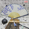 An elegant vintage Chinese folding hand fan with blue floral patterns displayed on a wooden stand.