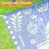 Blue papel picado bunting decorated with white cutouts, showing water droplets on the fabric.