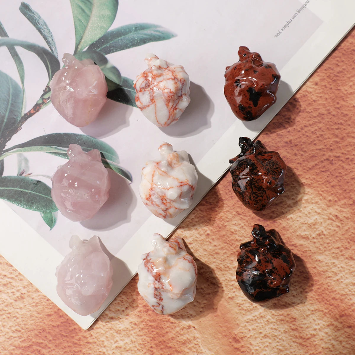 A collection of natural crystal heart carvings in various shades of pink and brown displayed on a light background.