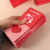A hand is holding a stack of red cards with the word surprise and heart decorations on them.