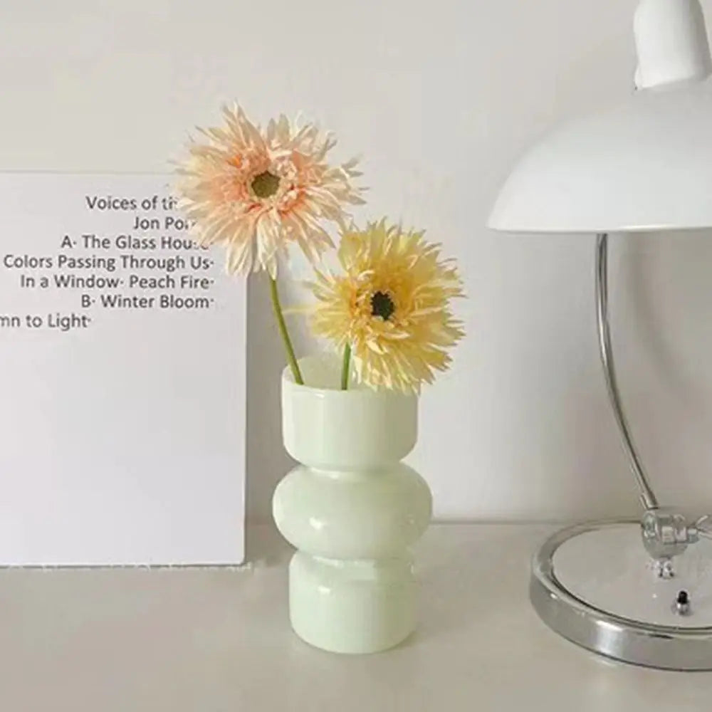 A white ceramic flower vase holding a dried orange-colored flower, next to a list of poem lines.
