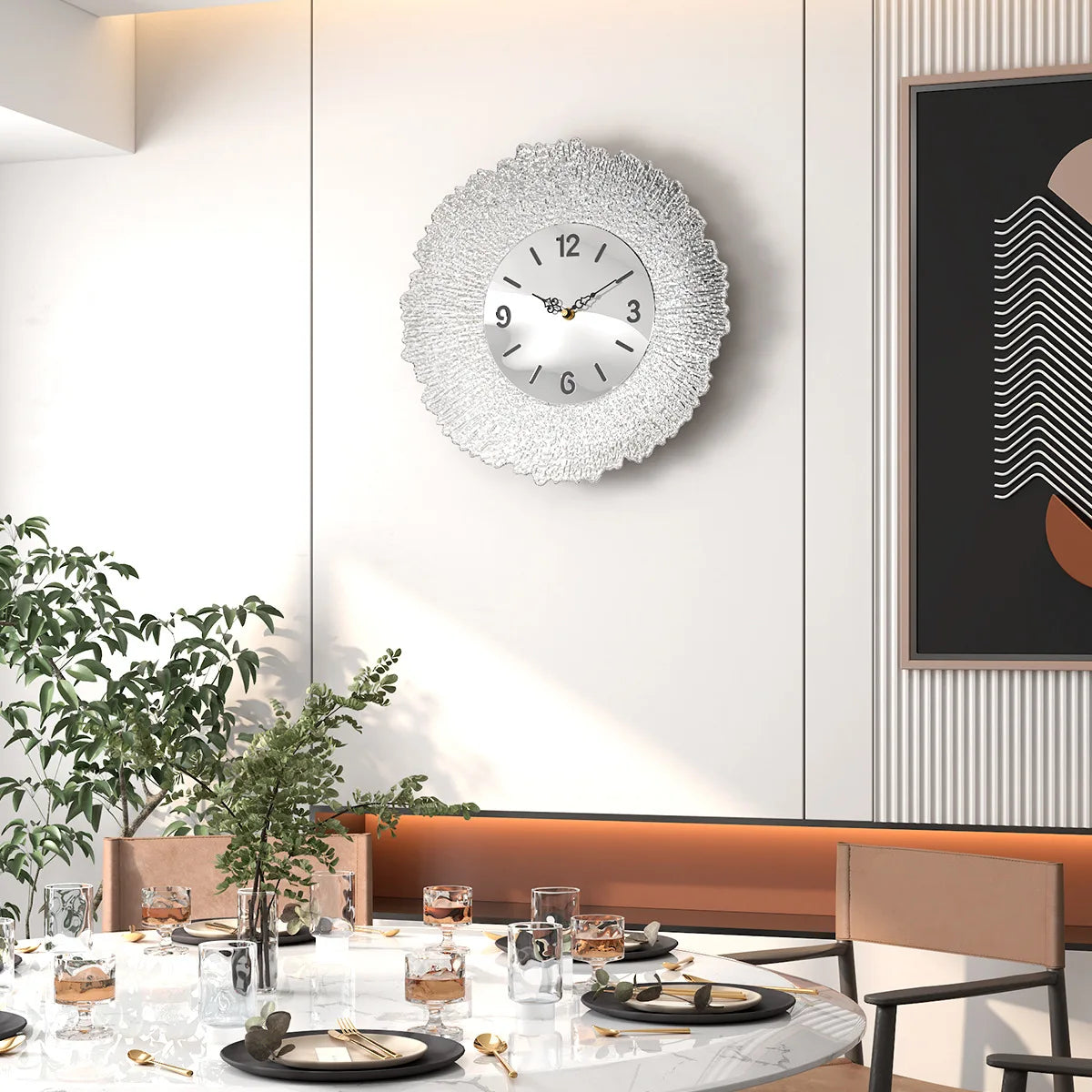 A modern silver wall clock with a white face and black numbers is mounted on a light gray wall in a contemporary interior.
